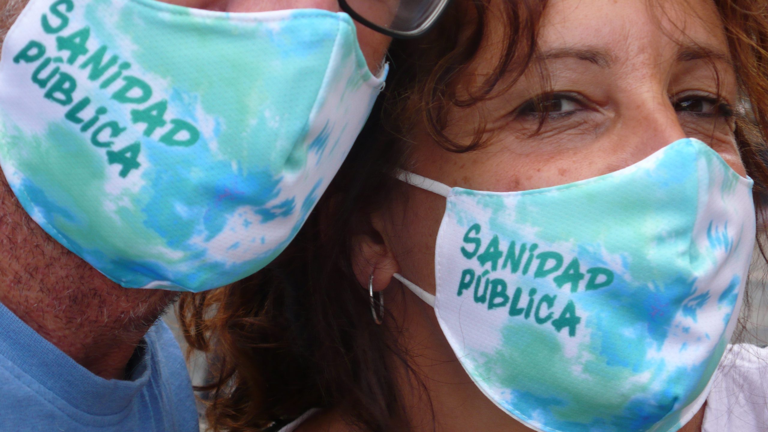 Dos personas llevando mascarillas por la sanidad pública